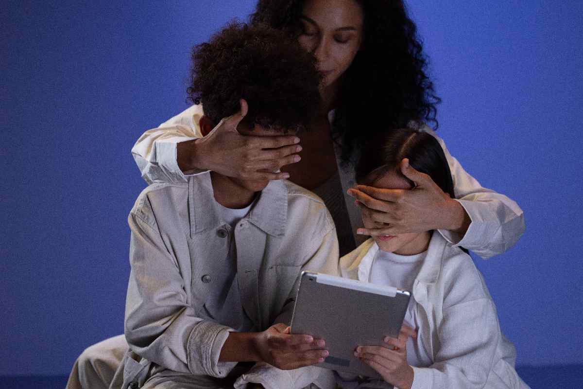 Una madre copre gli occhi dei figli per impedire loro di vedere lo schermo di un tablet