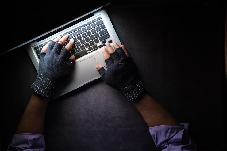 mani con guanti senza dita su computer portatile